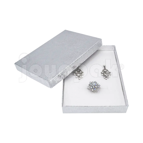 Un juego de collar y aretes de fiesta presentado de forma elegante dentro de la caja Fiore plateada grande abierta.