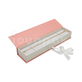 Caja Iberia de cartón texturizado rosa con tapa magnética para pulsera, caja abierta alargada mostrando una pulsera fina colocada sobre el inserto negro.